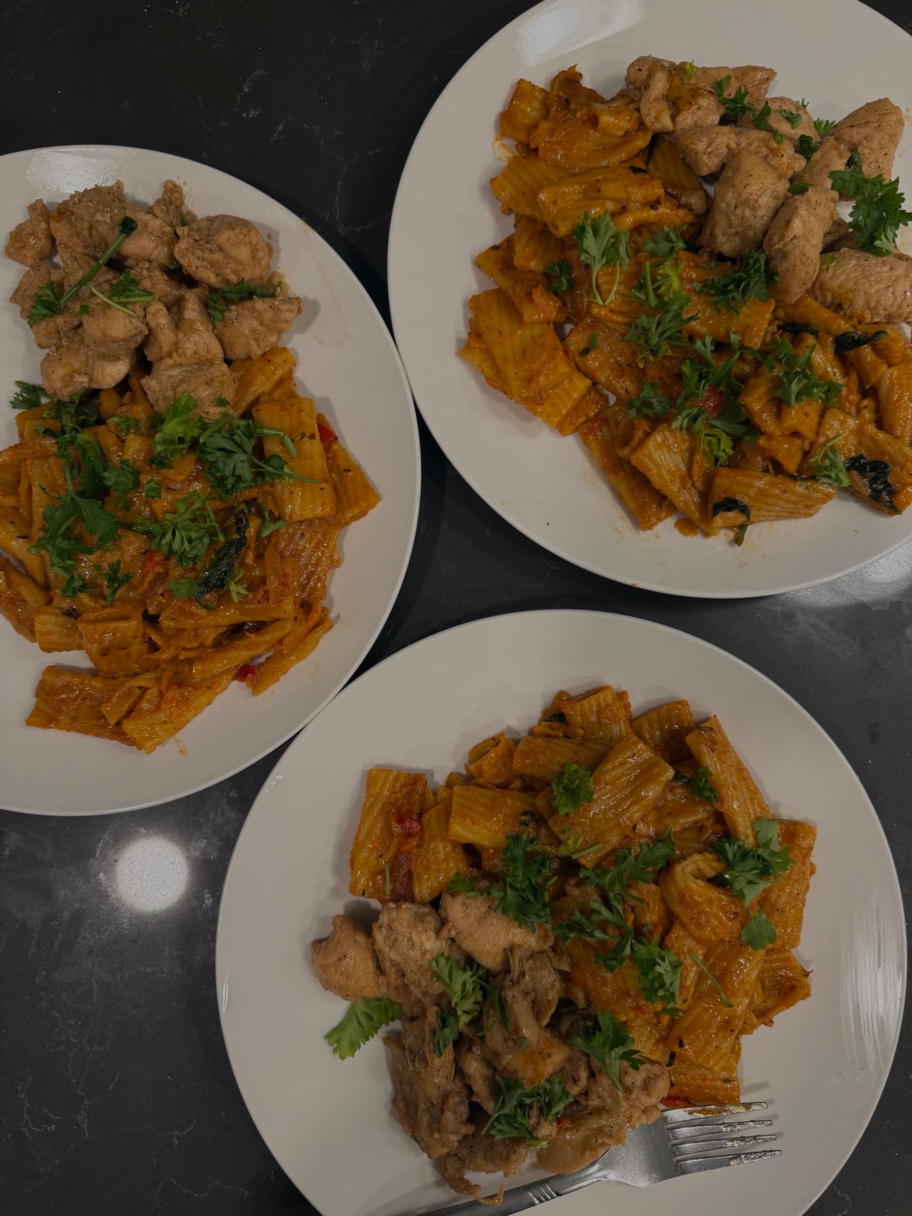 Plates of pasta with chicken and herbs.